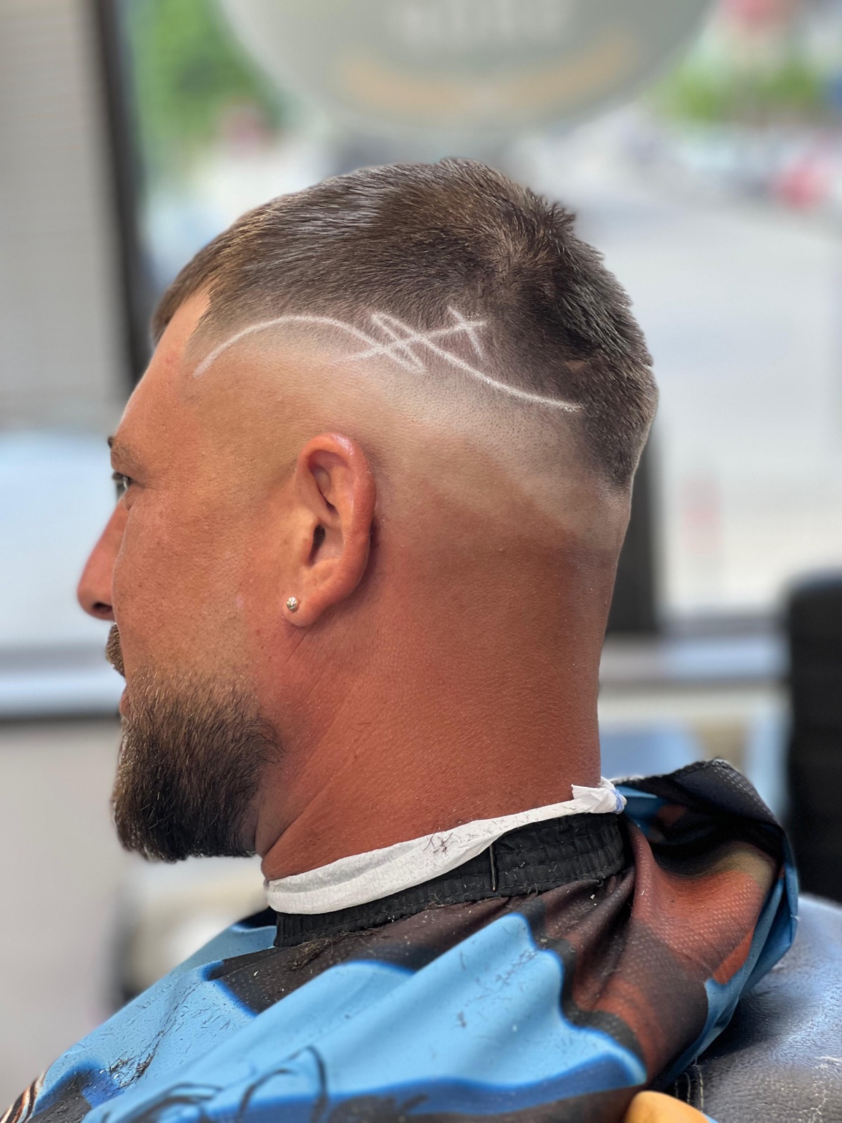 Skin fade cu design gravat pe o parte și barbă plină