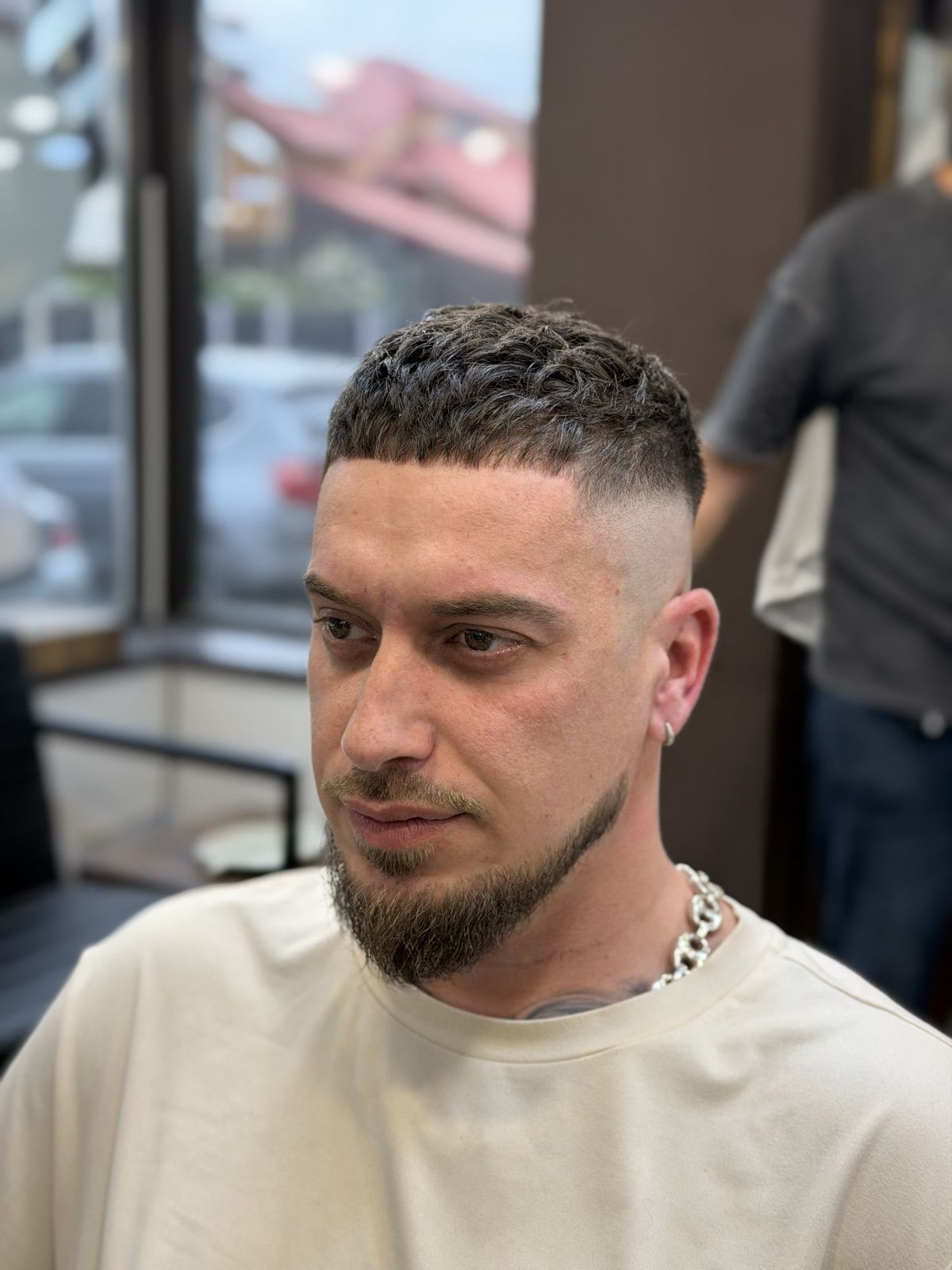 High skin fade cu păr aranjat sus și barbă conectată la fade