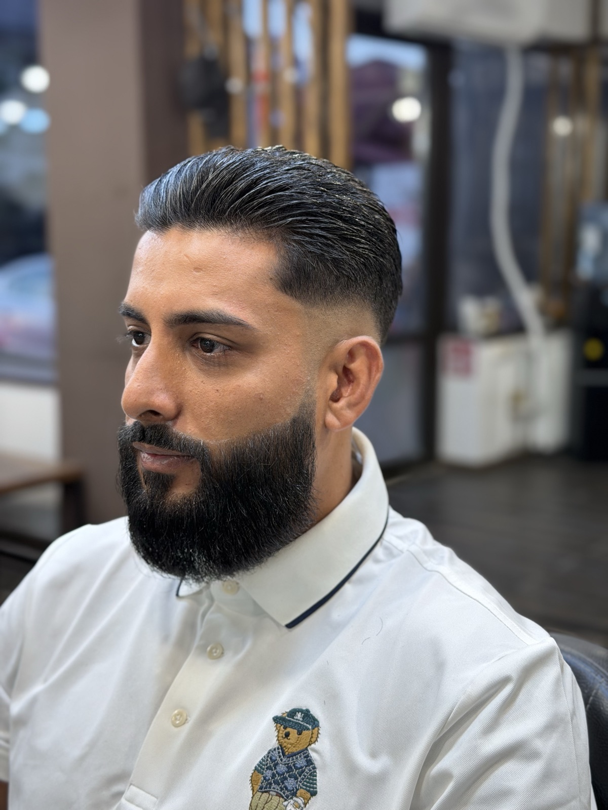 Slick back cu fade și barbă plină conturată precis